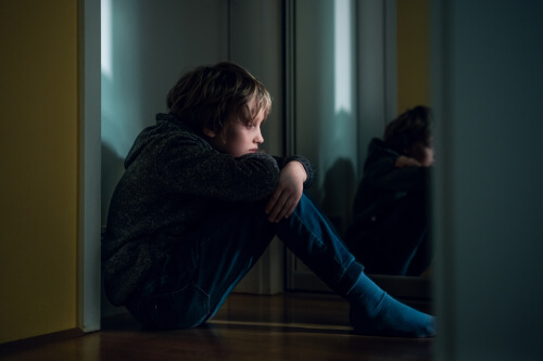 Sad 11 year old boy sat on floor